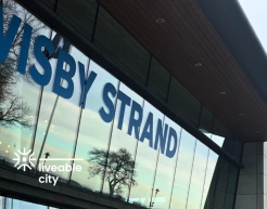 Ein Gebäude mit einer Glasfront auf der Visby Strand geschrieben steht. Unten links im Bild ist das Logo Liveable Cities