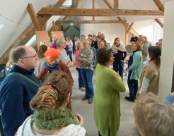 Menschen stehen in einem Raum und unterhalten sich. Der Raumcharakter ist geprägt von Balken an der Decke. 